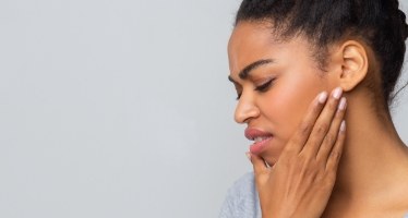 Person with jaw pain holding her cheek