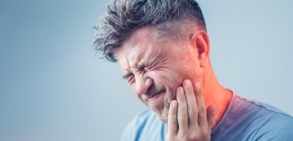 Man holding cheek in pain before restorative dentistry