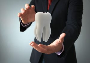 Dentist holding a tooth representing dental care.