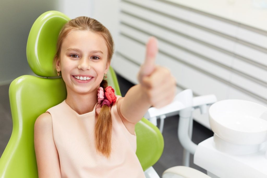 child giving a thumbs up at dentist's office